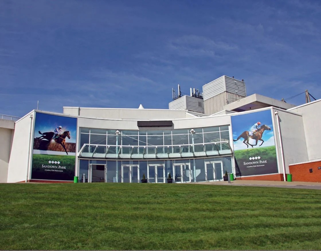 Racehorses thunder down the home stretch at Sandown Park Racecourse during the Flat Season Opener on April 25, 2025, under clear spring skies.
