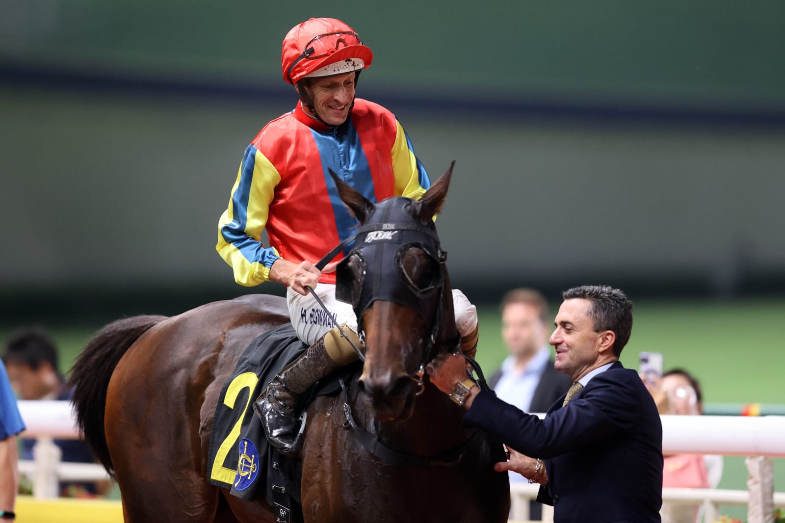 Hugh Bowman and Douglas Whyte celebrating a winning double at Happy Valley Racecourse under evening lights.