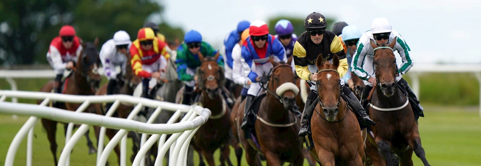 A lively scene at Carlisle Racecourse featuring flat horse racing action, enthusiastic spectators enjoying live music, and participants dressed in cowboy and cowgirl attire during the Anderson’s Boots and Bridles Race Day event.