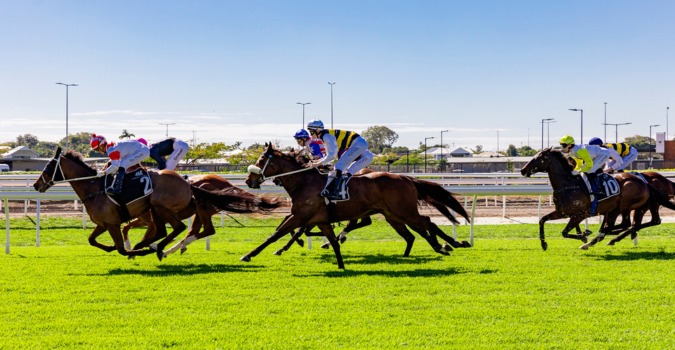 Thoroughbred horses racing down the straight at Doomben Racecourse during a midweek race day