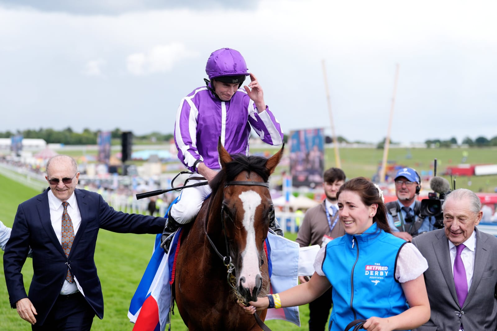 Apprentice jockey Ashley Lewis aboard Small Fry crossing the finish line during the Northern Dancer Handicap at Epsom Downs in wet track conditions.