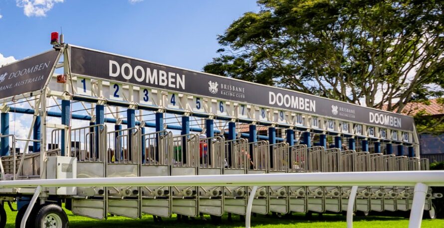 Crowds enjoying a sunny raceday at Doomben Racecourse with horses thundering past the finish line