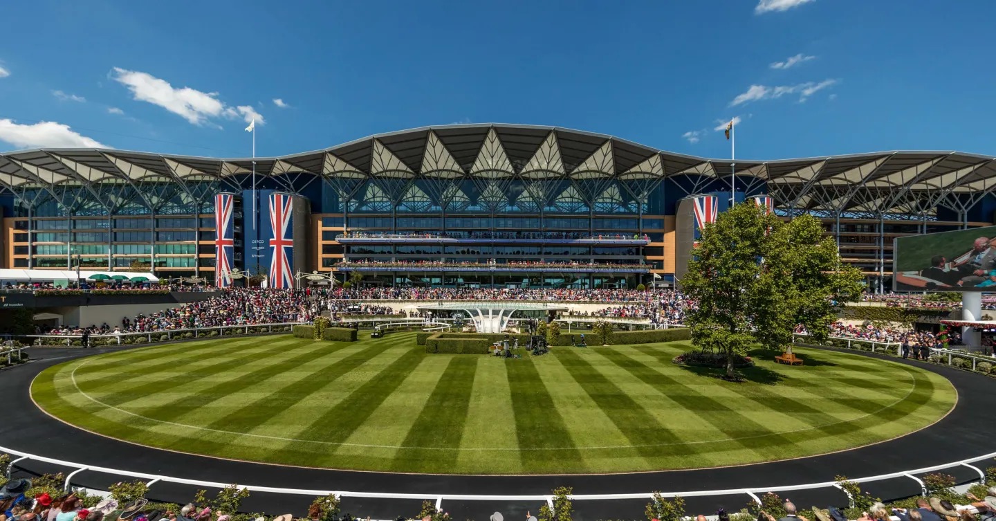 Crowds gather at Ascot Racecourse under bright summer skies as horses race down the historic turf track on the opening day of Royal Ascot.