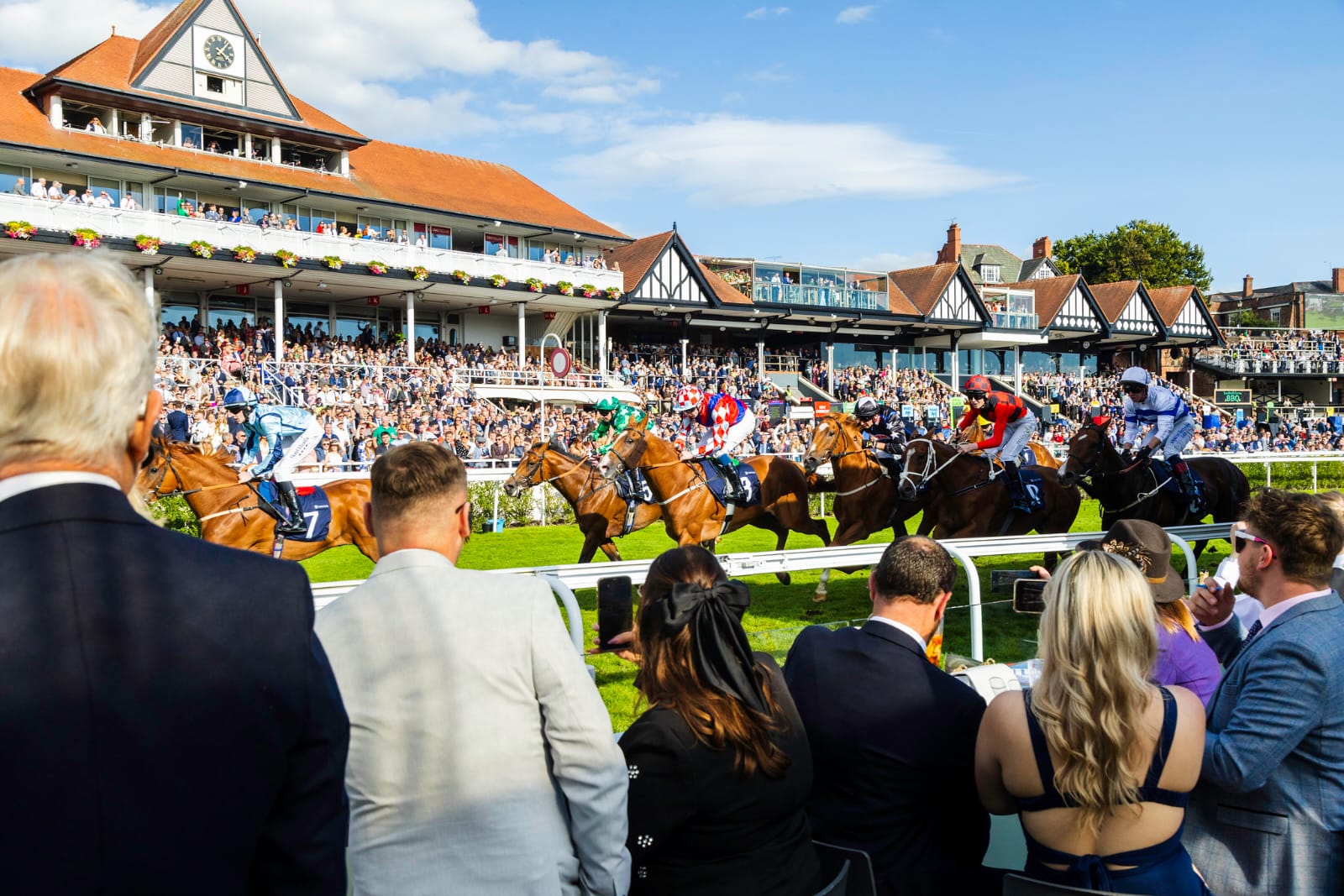 Racehorses in action during Chester Racecourse's Summer Social Weekend, set against vibrant summer crowds and live entertainment.