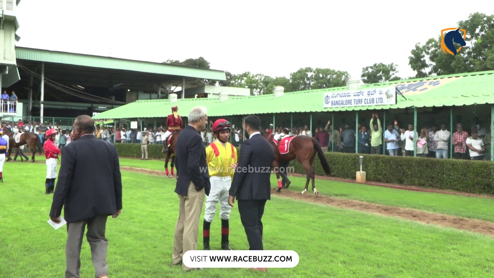 Horses breaking from the starting gates during a Bangalore Turf Club race on a sunny afternoon