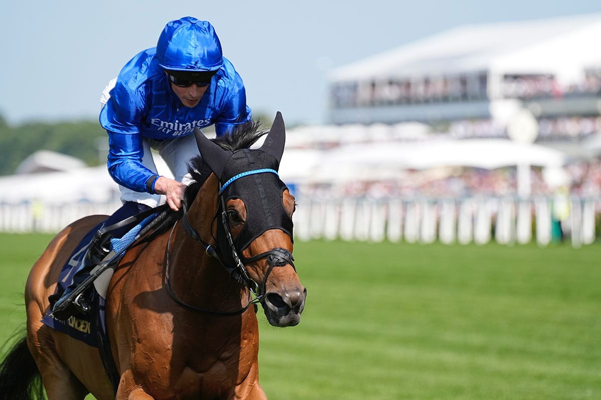 William Buick proudly holds a winner’s trophy after a major race victory, dressed in racing silks and smiling for the cameras—a moment that captures his success and stature in the world of flat racing.